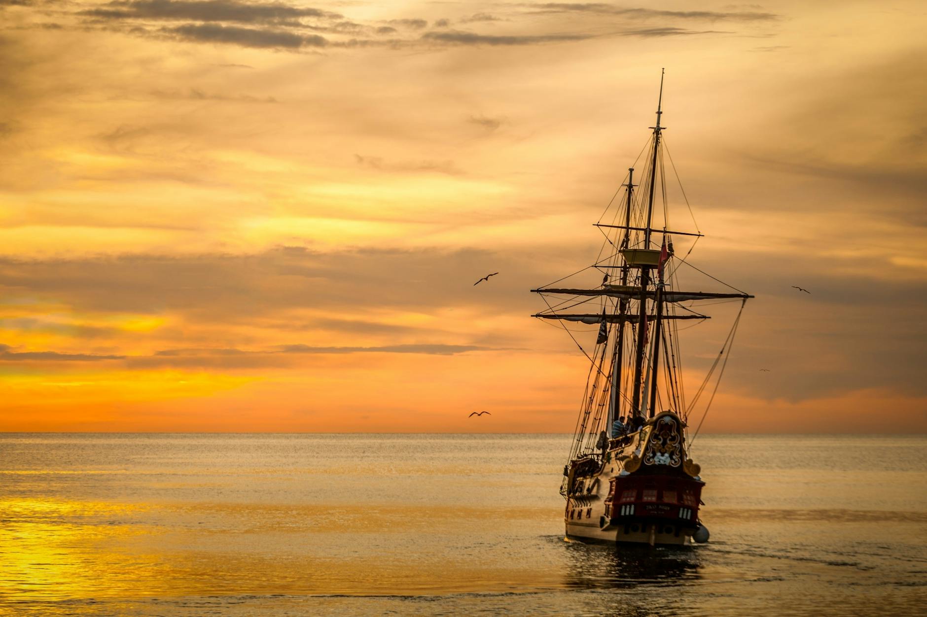 a pirate ship sailing on sea during golden hour